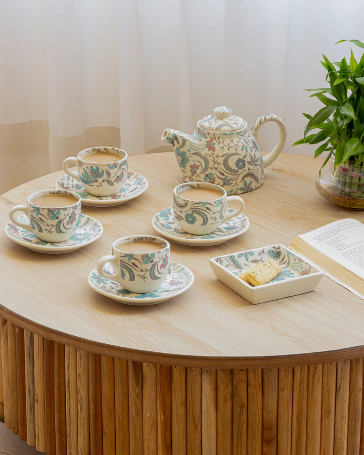 Tea set with teapot, cups, and saucers on a wooden table.
