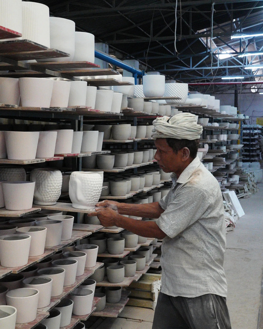 Man working with ceramic pots in a workshop setting