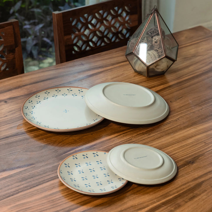 Four ceramic plates on a wooden table with a decorative lantern in the background.