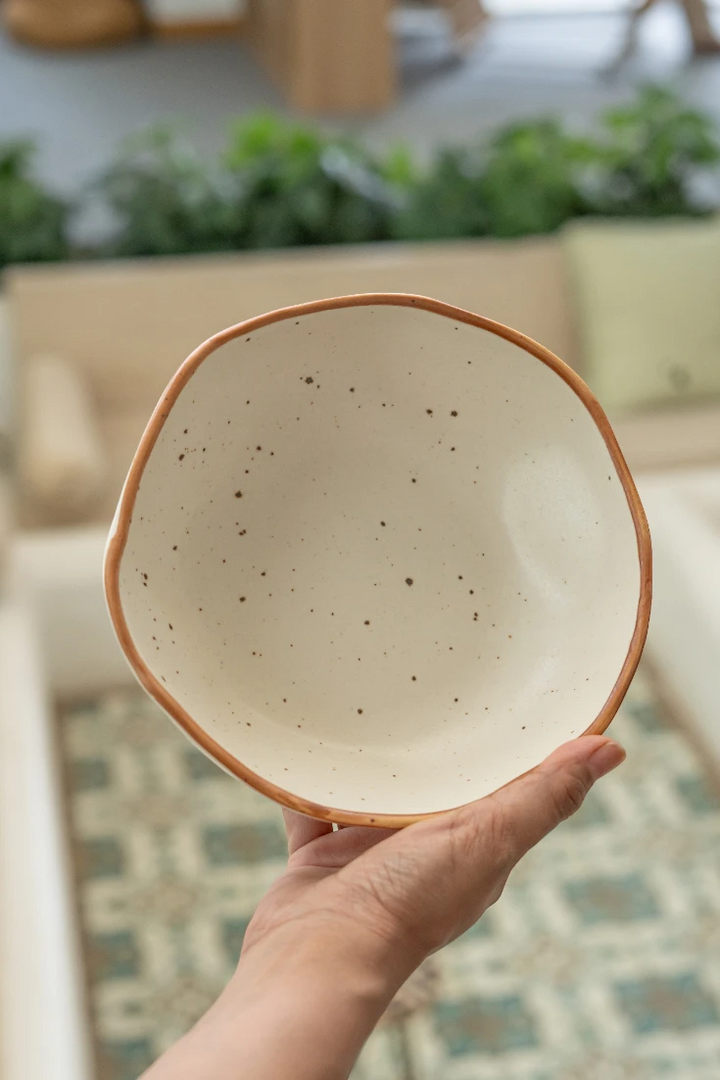 Ceramic bowl held in hand with blurred indoor background