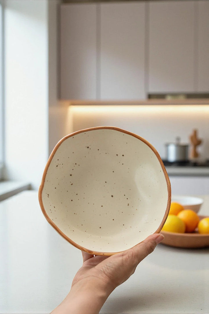 Hand holding a ceramic bowl in a kitchen setting