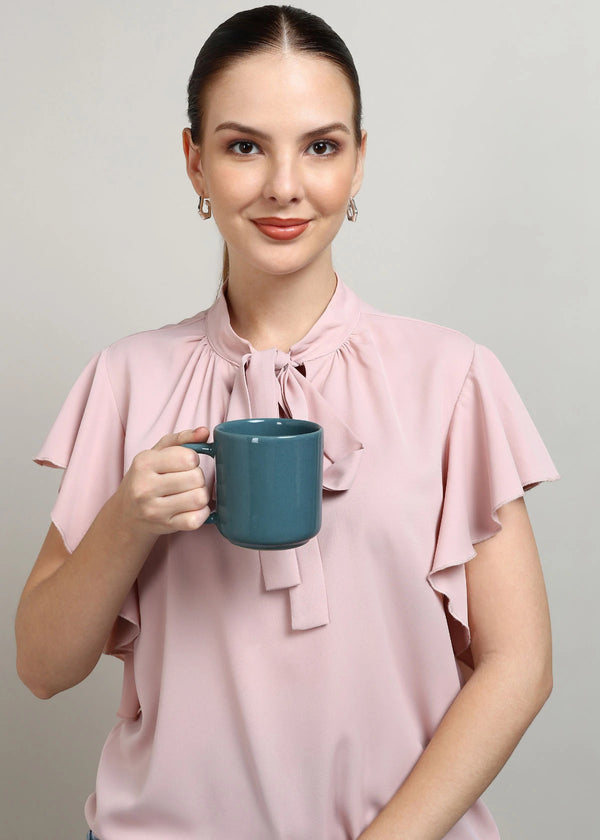 Woman holding a teal mug against a plain background