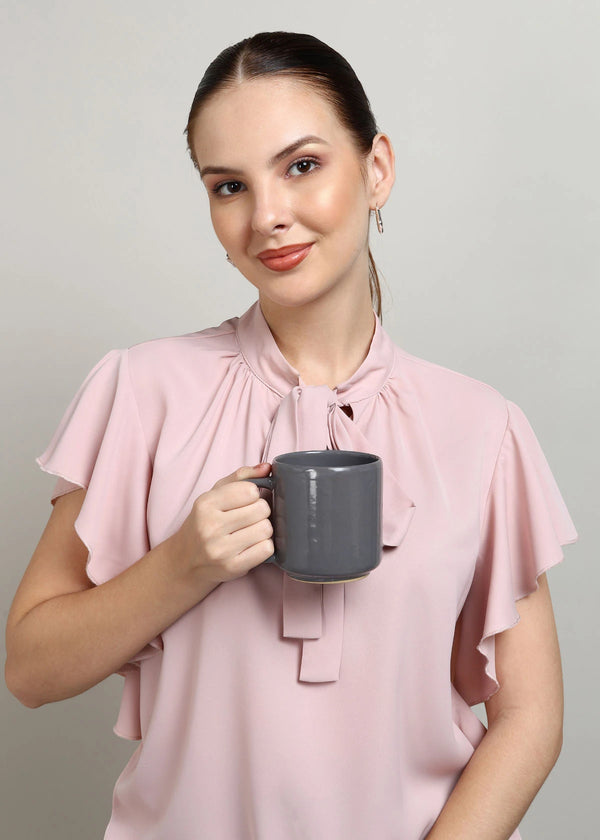 Woman in a pink blouse holding a Navy Blue mug against a plain background