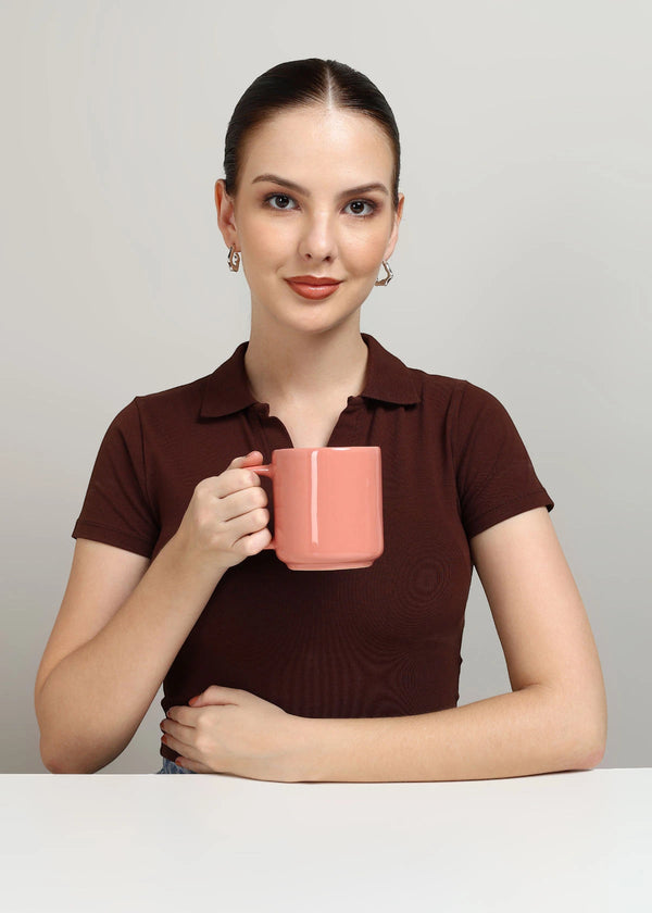 Woman holding a pink mug against a plain background