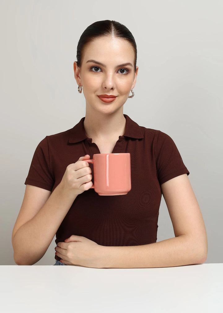 Woman holding a pink mug against a plain background