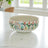 "Pink Dawn Bowl": 500ml luxury ceramic bowl online, adorned with pink flowers. Use its wide mouth to showcase small floral arrangements; shop this artisan dual-purpose bowl from Claymistry – both a serving dish and unique table centerpiece.