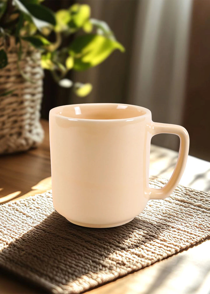 Beige mug on a textured surface with a blurred plant in the background