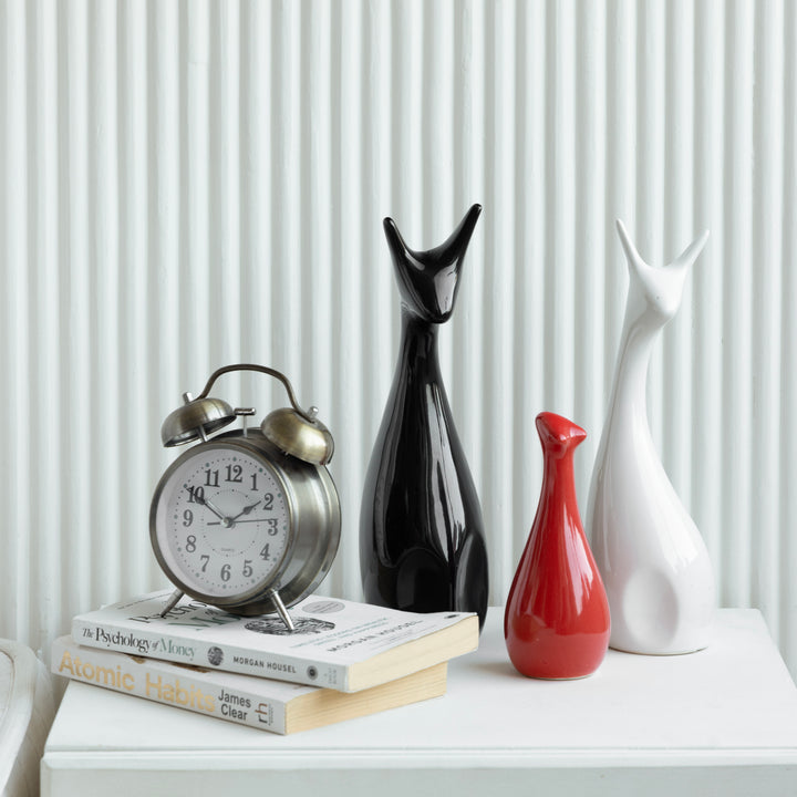 3 ceramic deer-shaped figurines, perfect for home decoration, on a white cabinet with books & clock