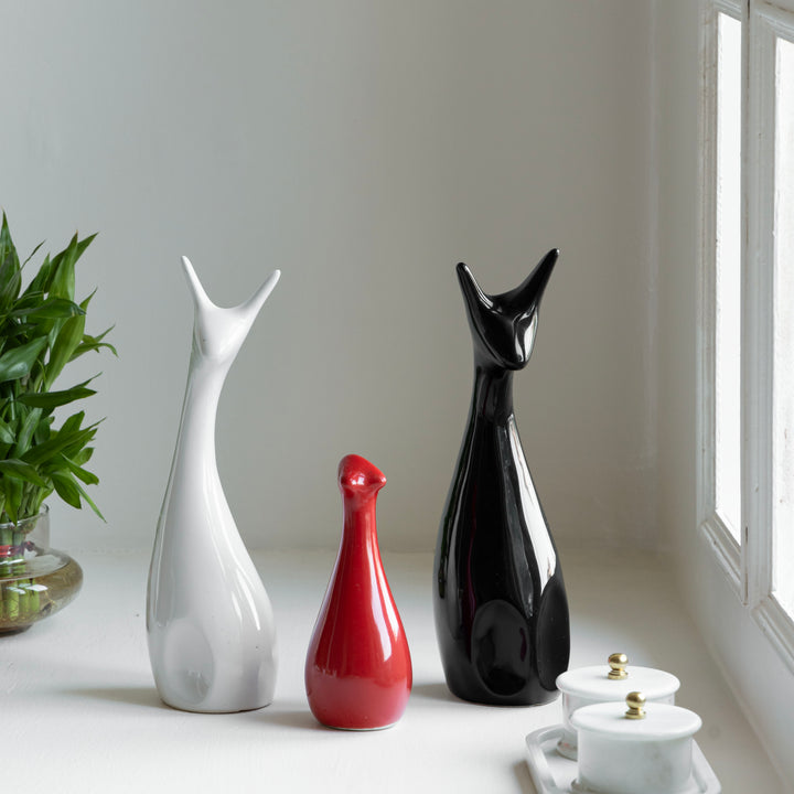 3 ceramic deer-shaped figurines on a windowsill beside indoor plants