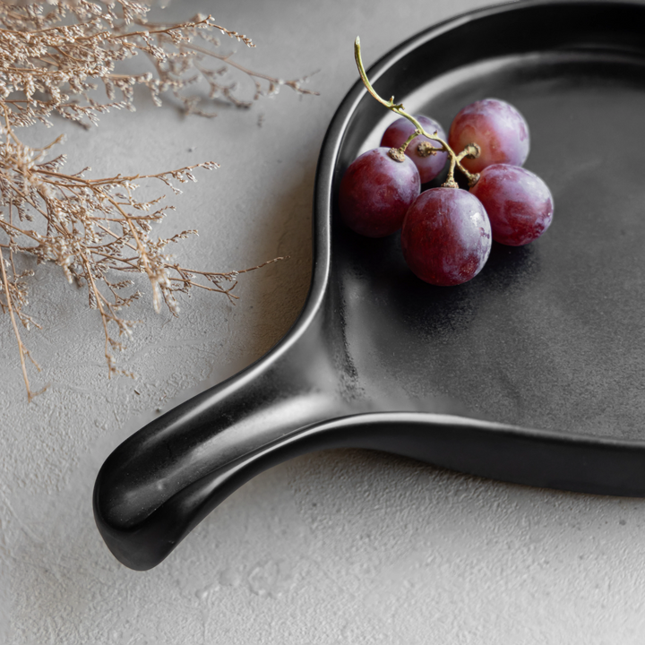 Spill-proof black ceramic platter with handle, durable and dishwasher friendly with fine glaze.
