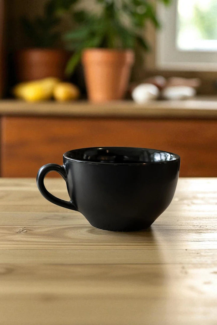 Black mug on a wooden table with a blurred kitchen background