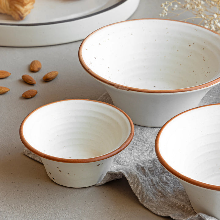 Small handcrafted ivory ceramic bowl with specks and brown rim, safe, durable and microwave safe.