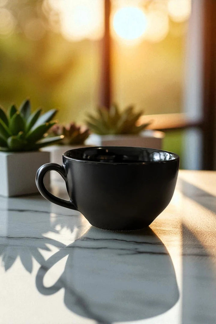 Black mug on a marble surface with plants and blurred background