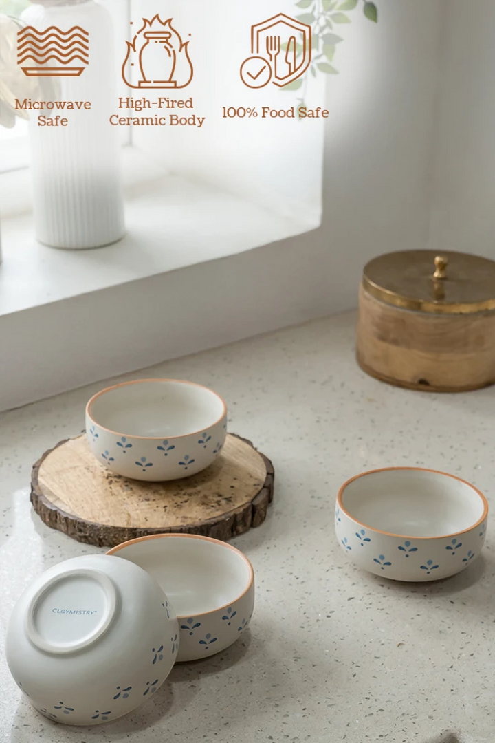 Set of ceramic bowls on a light surface with icons indicating microwave safety, high-fired ceramic body, and food safety.